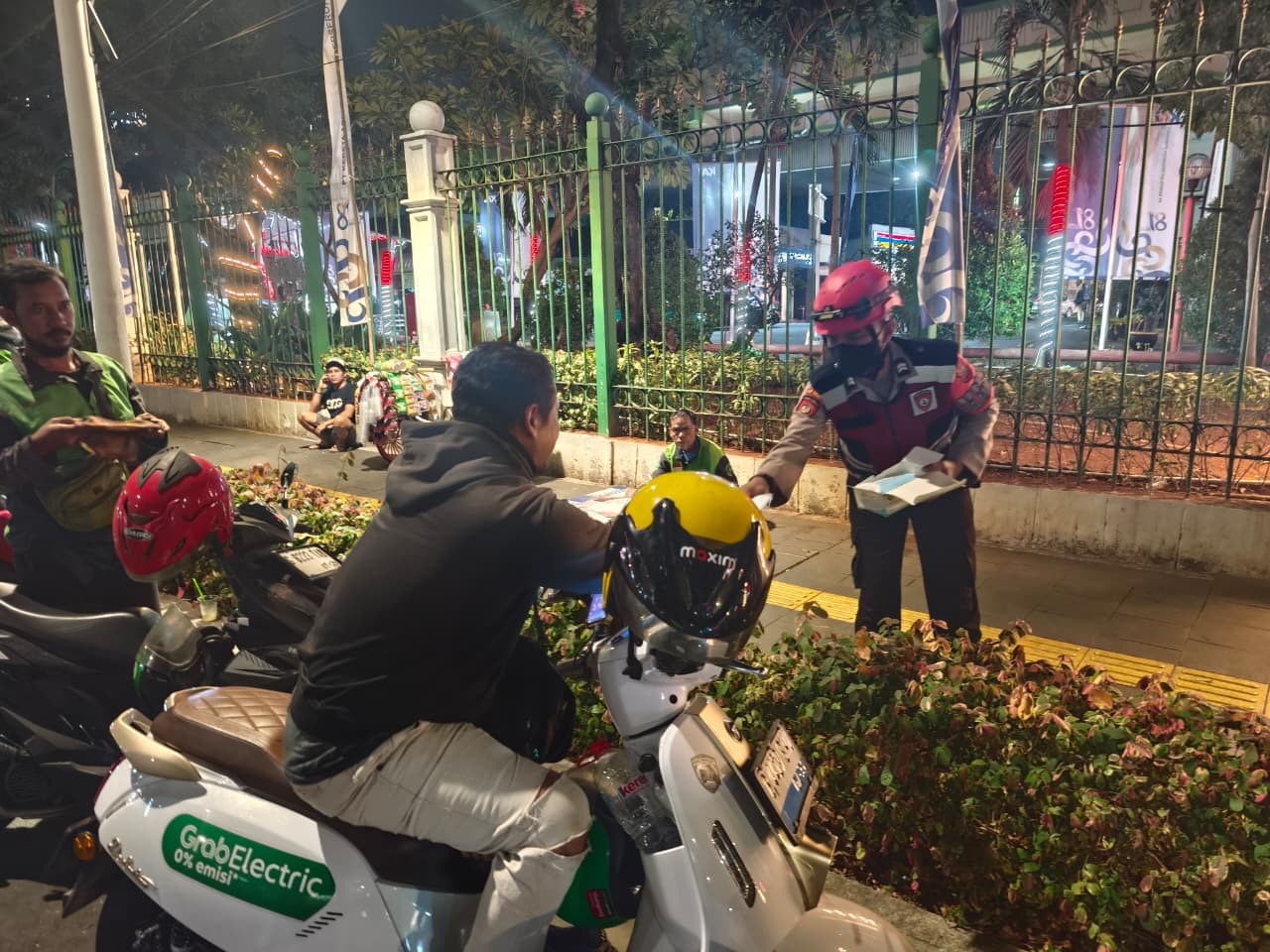 POLISI BAGIKAN MASKER KEPADA MASYARAKAT DI STASIUN GAMBIR ANTISIPASI DAMPAK ABU VULKANIK GUNUNG ANAK KRAKATAU